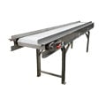 Cinta transportadora de acero inoxidable apta para el contacto con alimentos, con banda modular de plástico blanco, rieles laterales y patas de soporte, utilizada para el transporte higiénico de productos alimenticios en plantas procesadoras.